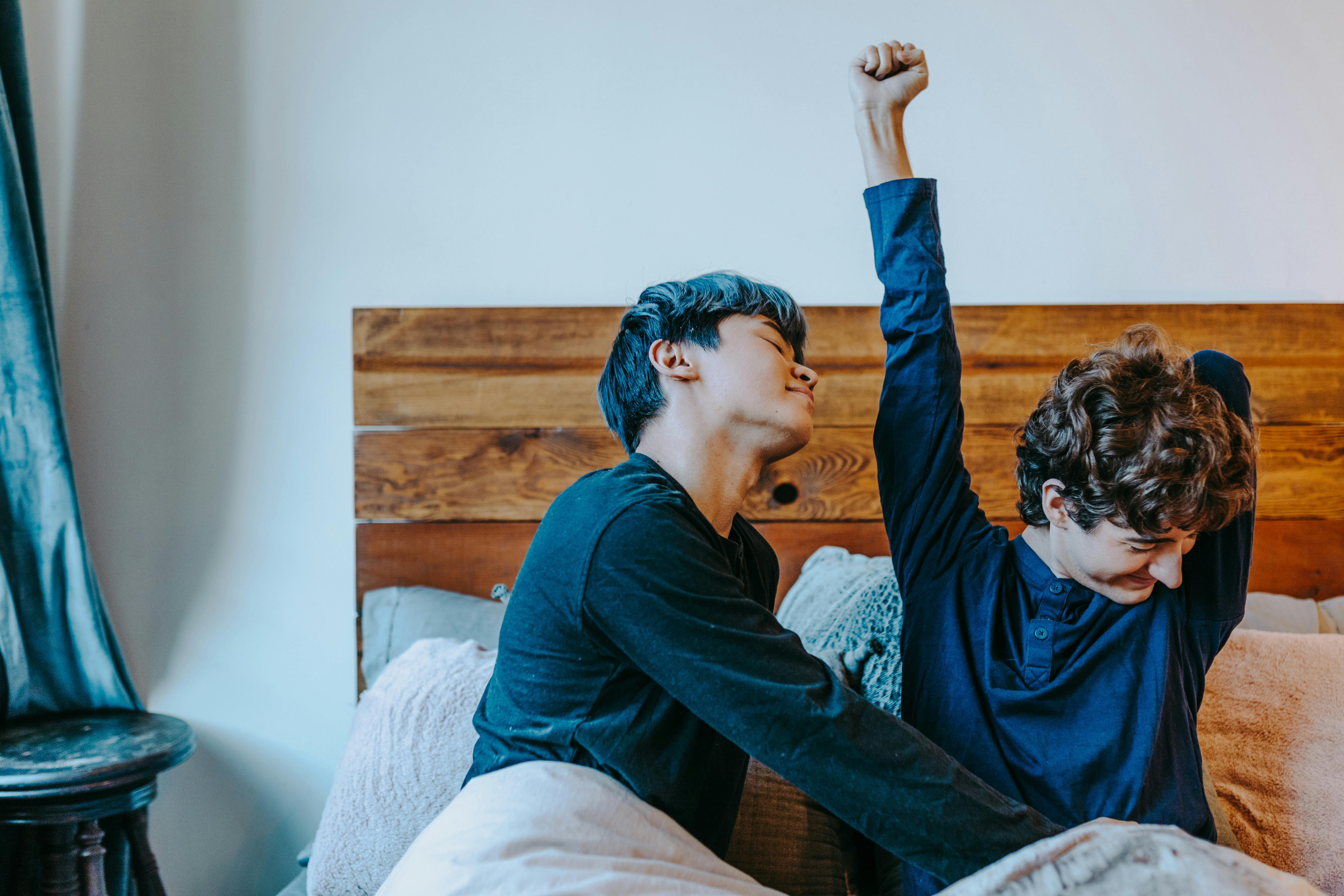 man in blue sweater sitting on bed