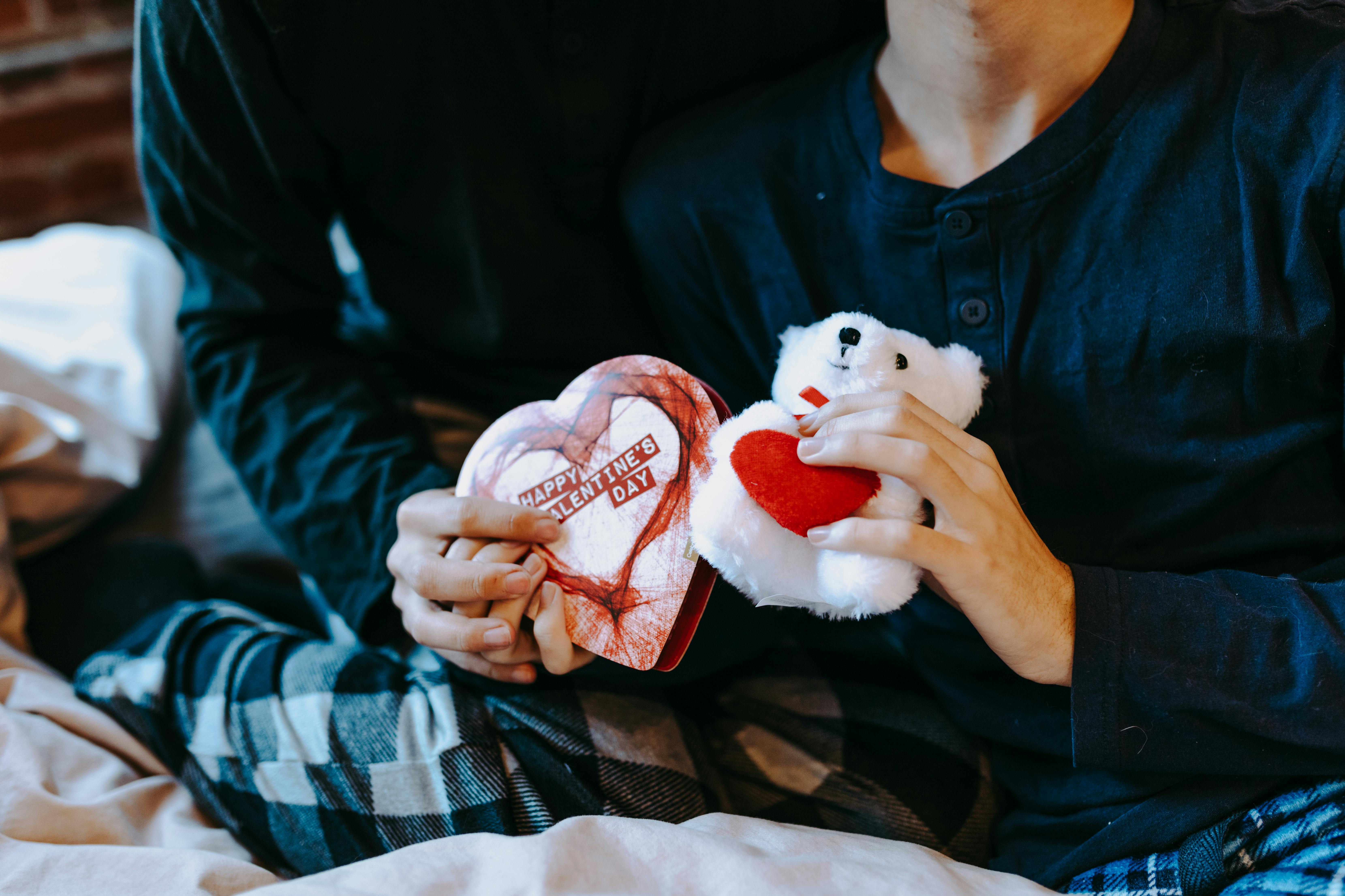 person holding white and red bear plush toy