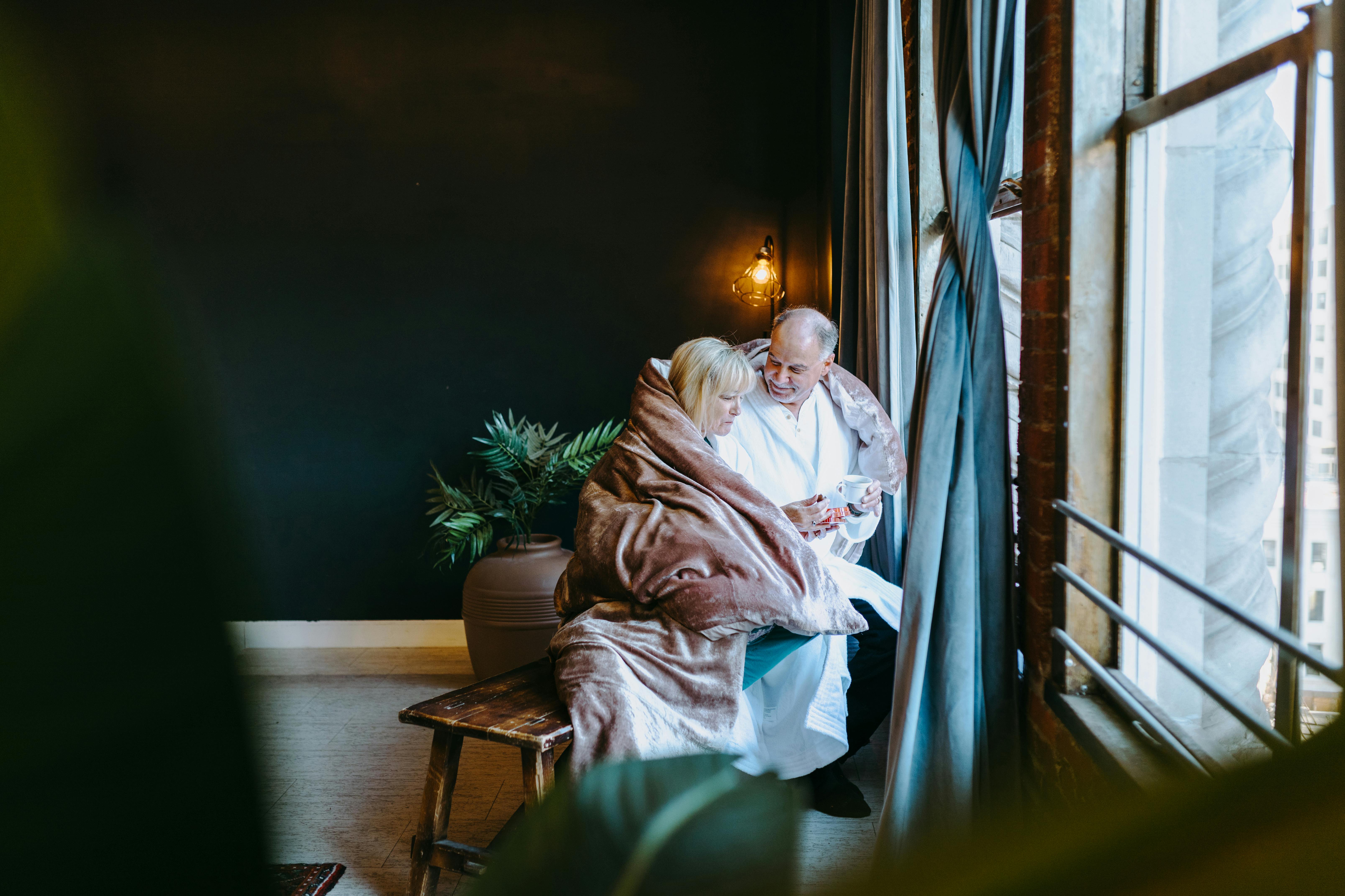 man and woman sitting on brown wooden framed brown padded armchair