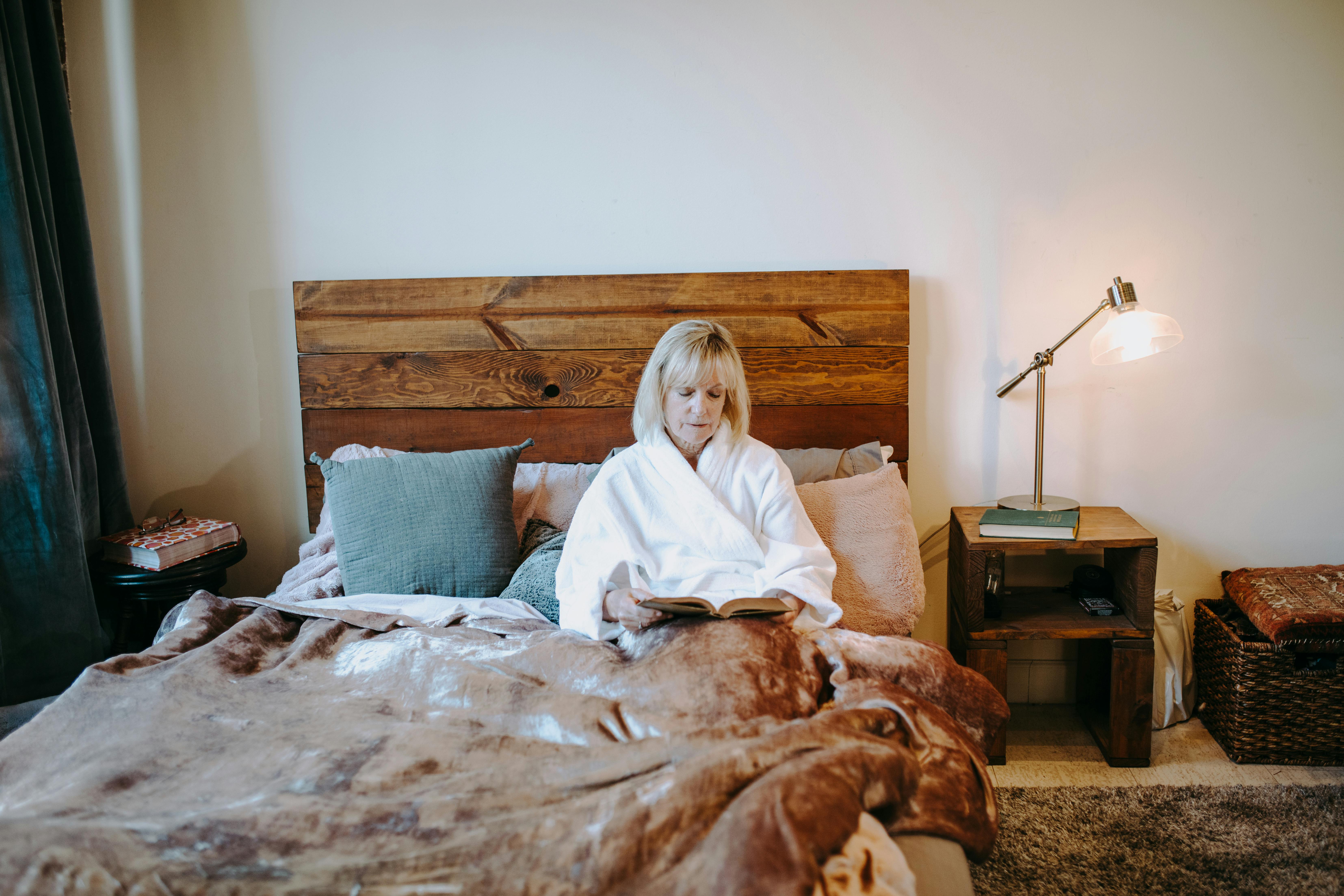 woman in white robe sitting on bed