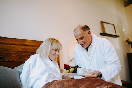 Free A Man Giving a Woman Breakfast in Bed Stock Photo
