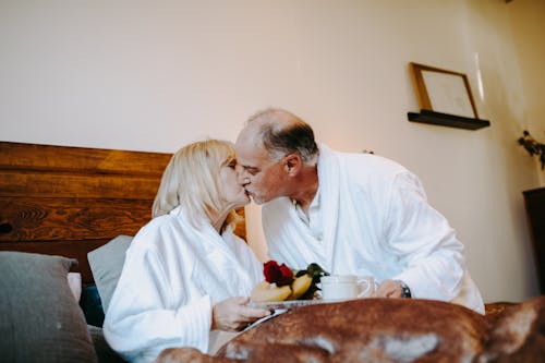 Photograph of an Elderly Couple Kissing on the Bed