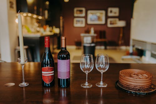 A Wine Bottles and Glasses on a Wooden Table Near the Chocolate Cake