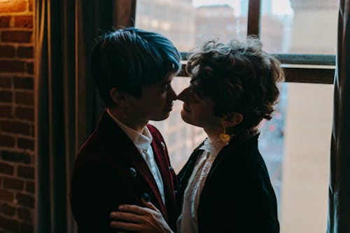 Free A Couple Kissing Near a Glass Window Stock Photo