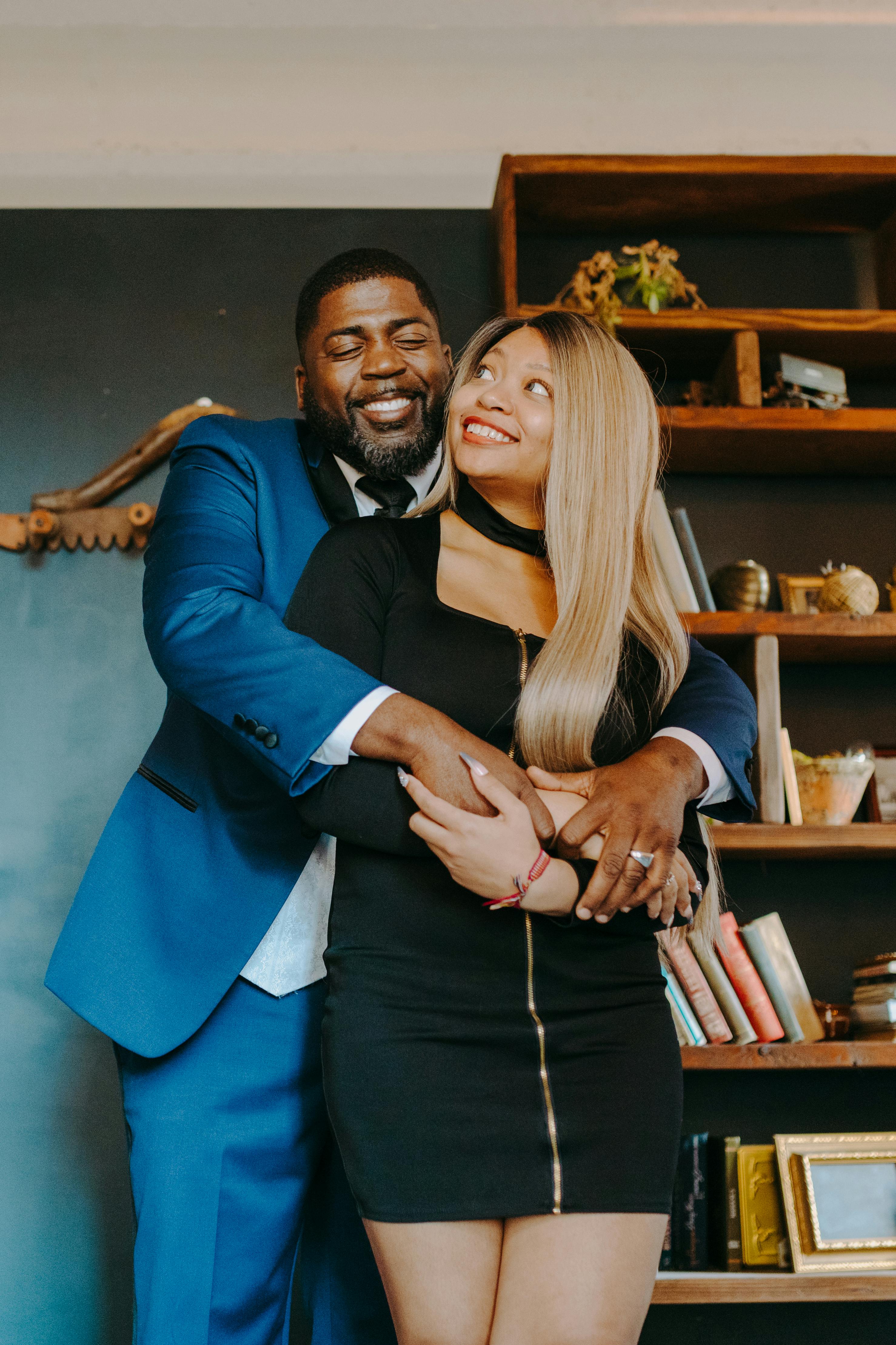 Man in Blue Suit Jacket Hugging Woman in Black Dress  Free Stock Photo