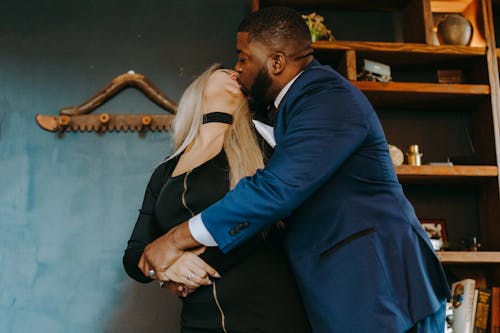 Photo of a Man in a Blue Suit Kissing a Woman
