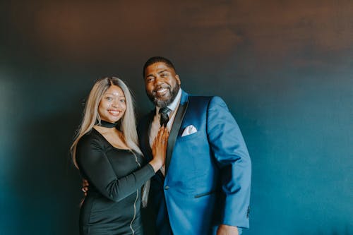 Photo of a Man in a Blue Suit Smiling Beside a Woman in a Black Dress