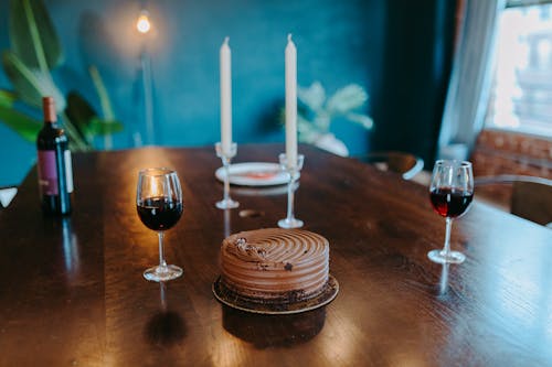 A Chocolate Cake on a Wooden Table Near the Wine Glasses