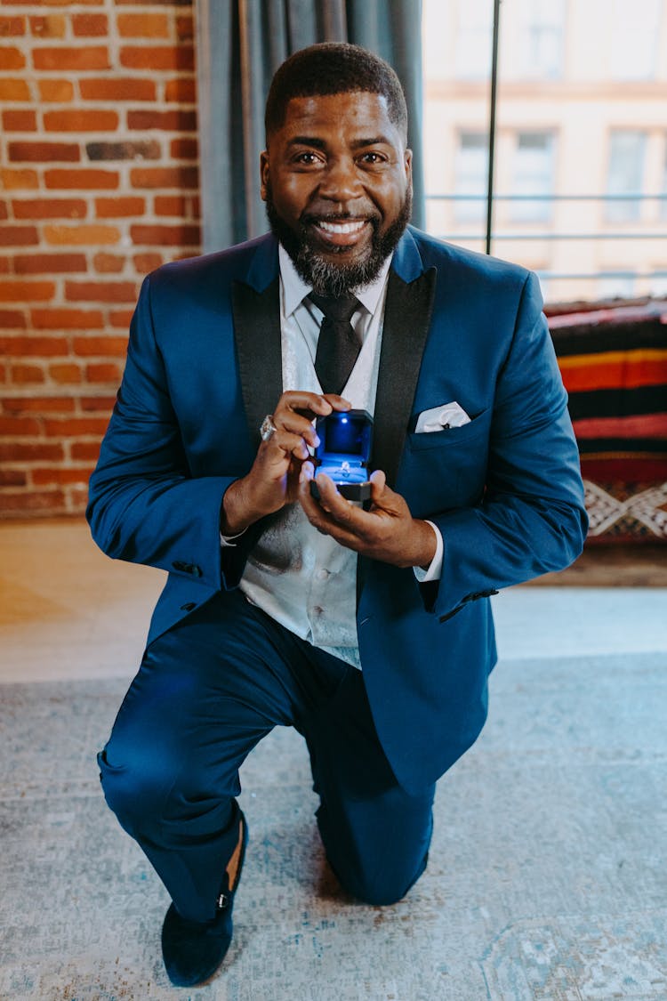 A Man In Blue Suit Kneeling While Proposing