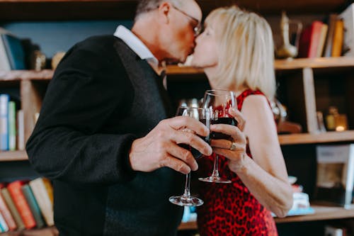 Free Photo of an Elderly Couple Kissing while Holding Glasses of Wine Stock Photo