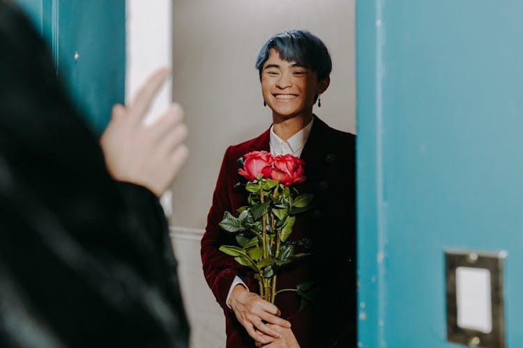 A Man Holding Flowers While Standing At The Door