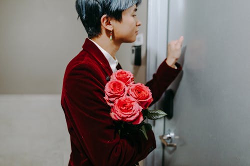 A Man in Red Suit Holding a Red Roses while Knocking on the Door