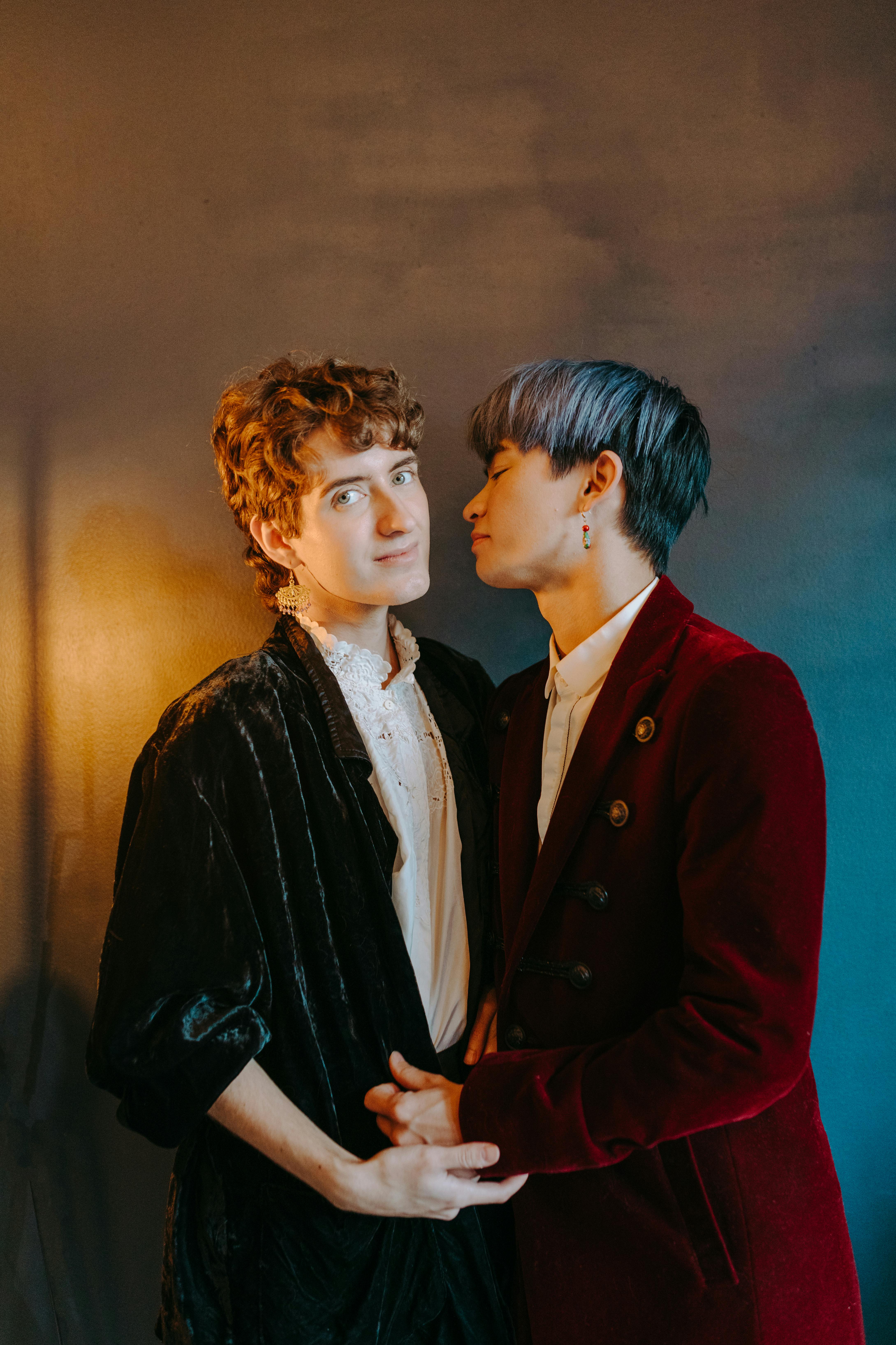 a couple wearing formal attire standing near the brown background