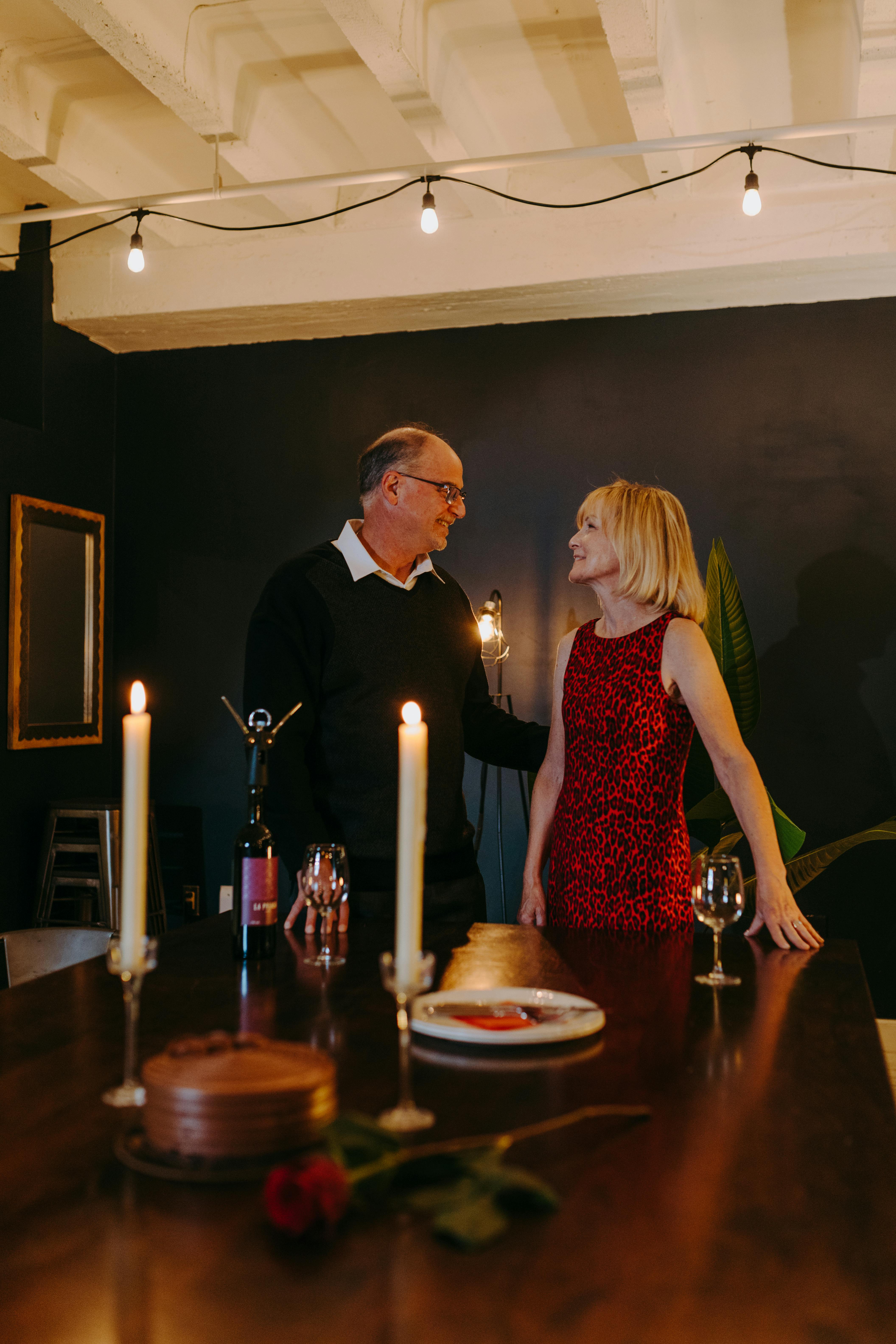 Elderly couple enjoying a romantic dinner setting indoors with candles and wine.