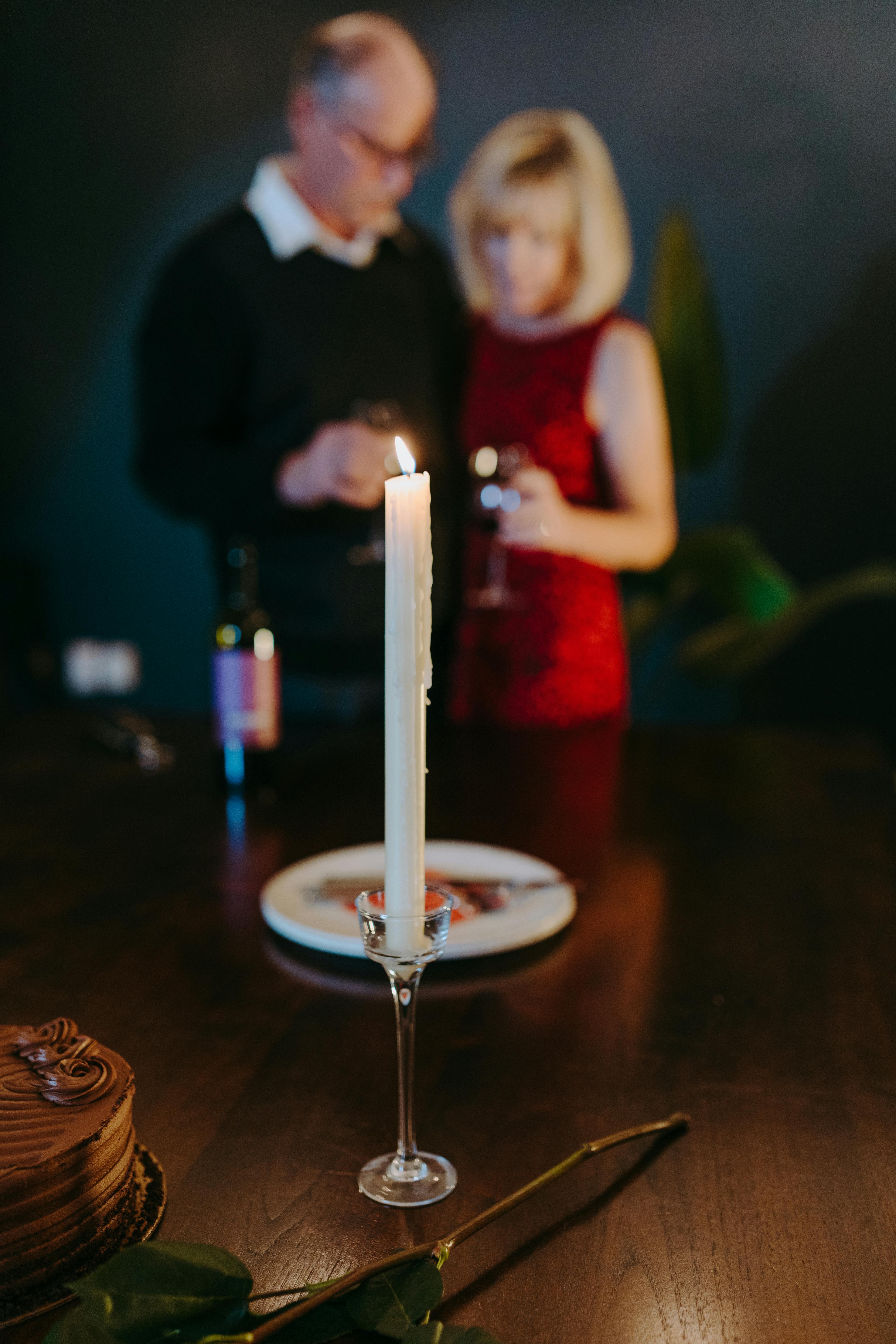 Candlelit dinner setting with a couple enjoying wine, creating a romantic atmosphere.