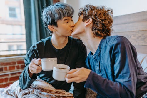 Free Photograph of Men Kissing while Holding Cups Stock Photo