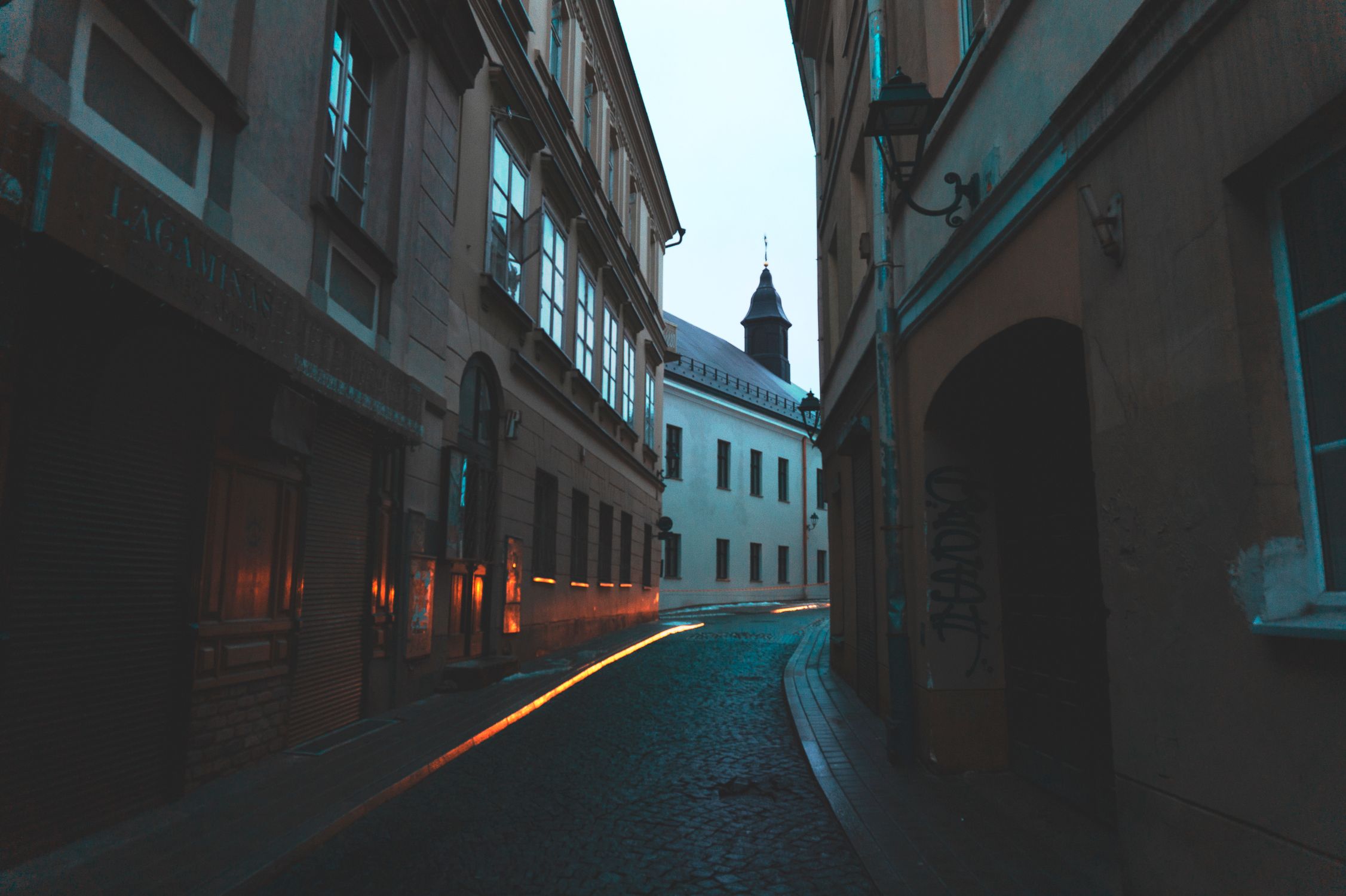A moody urban street scene in Vilnius, featuring quiet cobblestone paths at twilight.