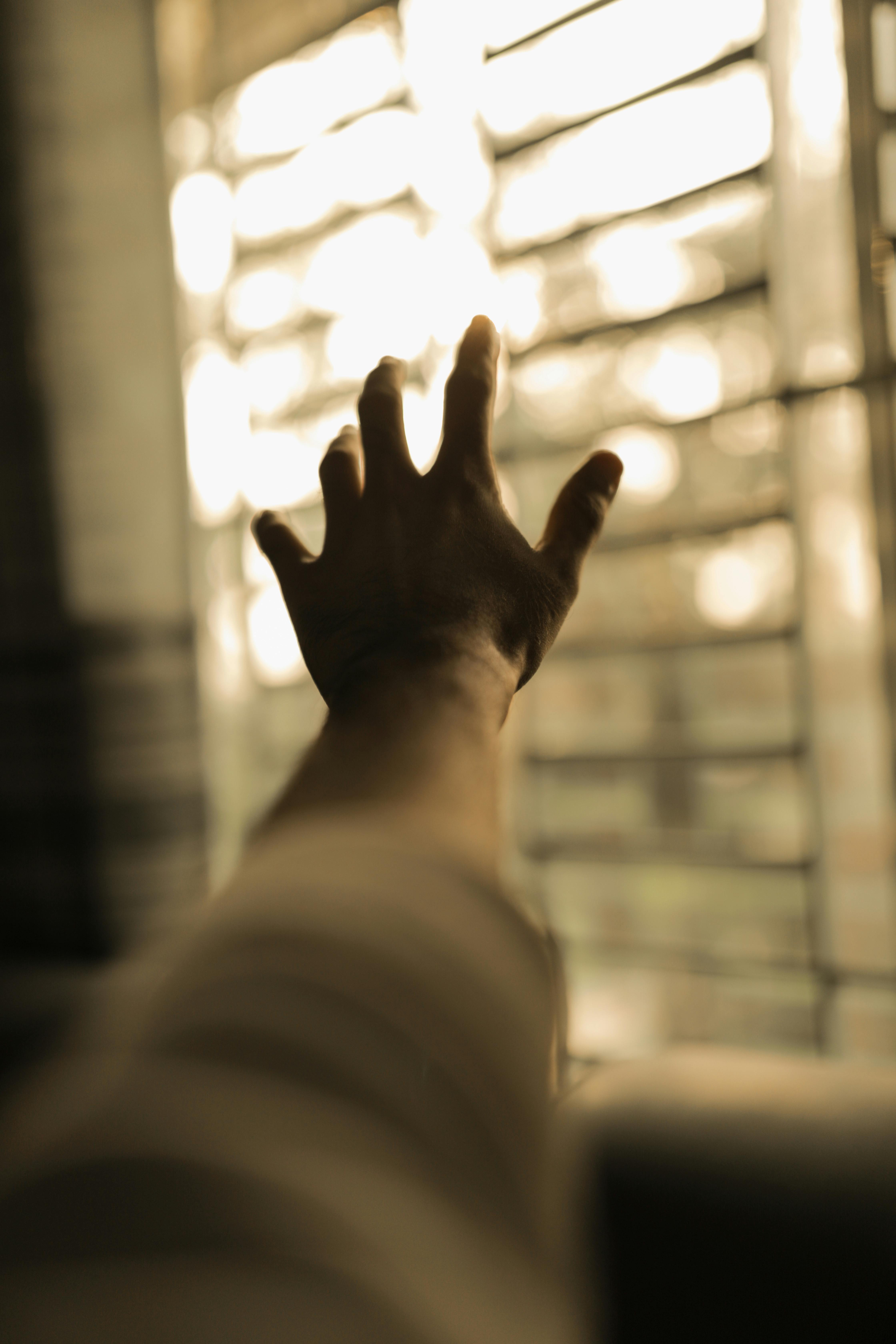unrecognizable person reaching hand to window