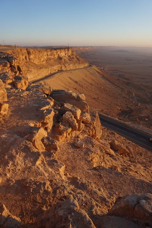 Free A breathtaking view of Mitzpe Ramon crater showcasing the rugged desert landscape and winding road. Stock Photo