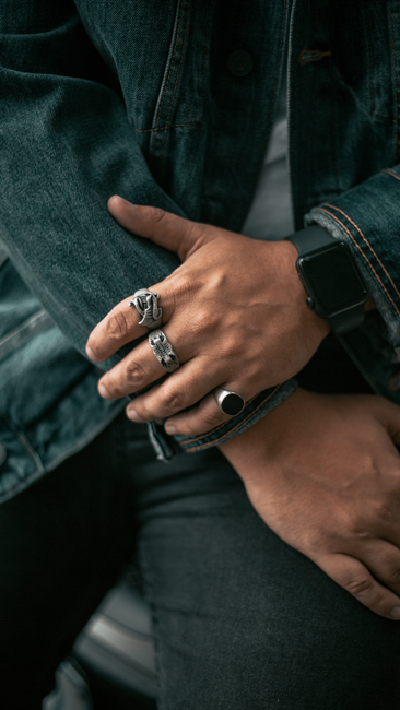 Detailed close-up of hands wearing rings and a smartwatch, showcasing style and technology.