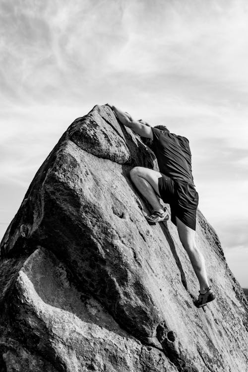 Free A Grayscale Photo of a Man Climbing on the Rock Stock Photo