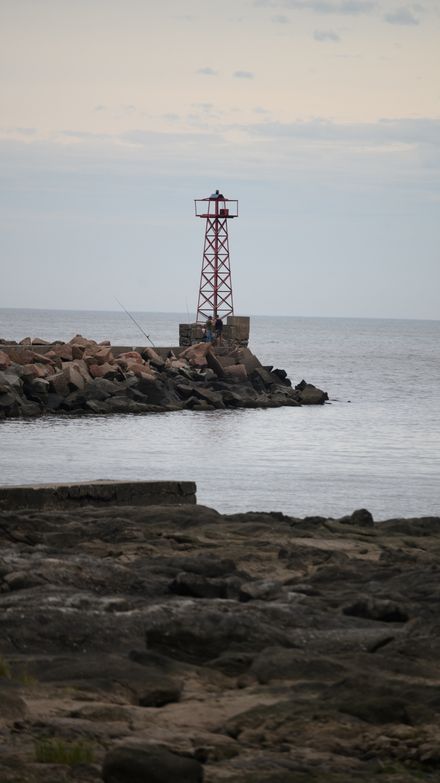 Light tower on a rocky coastline photo by Invisible Look on Pexels