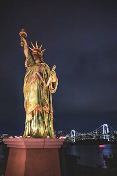 Night view of Tokyo's Statue of Liberty with cityscape in background.