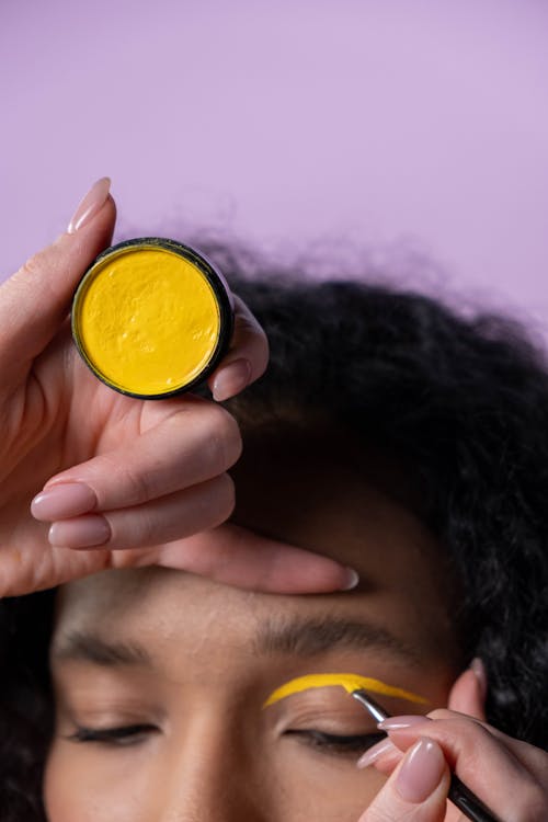 Hands of a Person Holding and Applying Eye Makeup