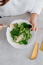 Person Holding Green Vegetable Salad on White Ceramic Plate
