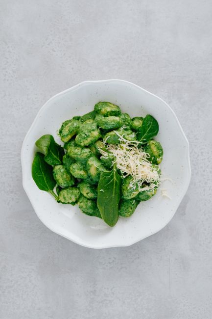 A plate of vegan spinach gnocchi topped with fresh parmesan cheese.