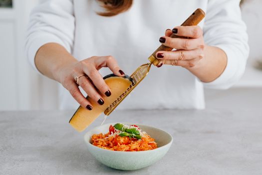 Photo of a Woman Grating Cheese on Top of a Risotto