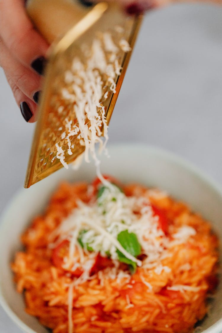 A Person Grating A Cheese