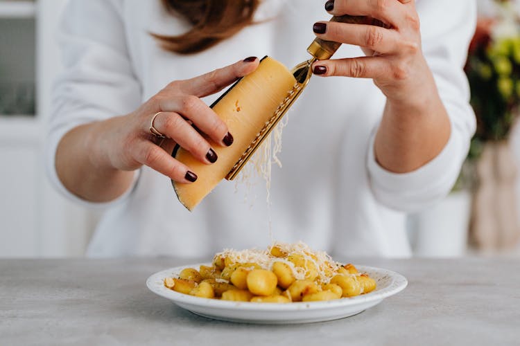 A Person Grating A Cheese On A Gnocchi