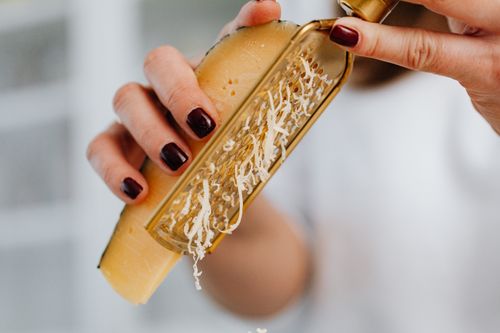 Free Close-up image of grated parmesan cheese with focus on hands and food preparation. Stock Photo