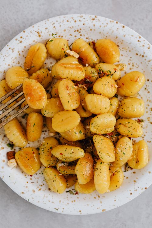 Free Mouth-watering Italian gnocchi seasoned with fresh herbs served on a ceramic plate. Stock Photo
