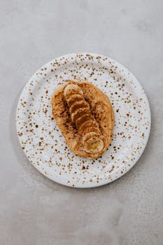 Artistic flat lay of peanut butter banana toast on a speckled plate.