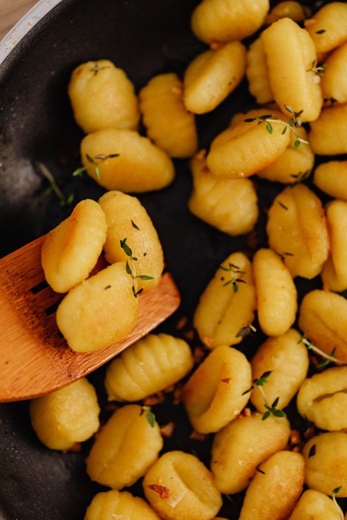 Free Close-up of golden homemade Italian gnocchi garnished with herbs in a pan. Stock Photo