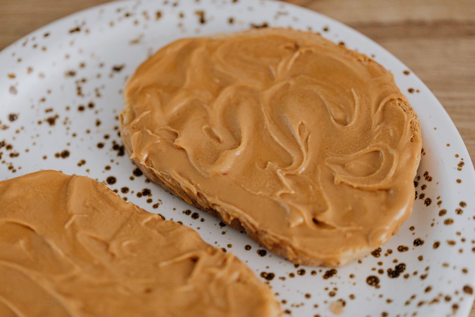 Creamy peanut butter spread on toast on a speckled plate, delicious breakfast idea.