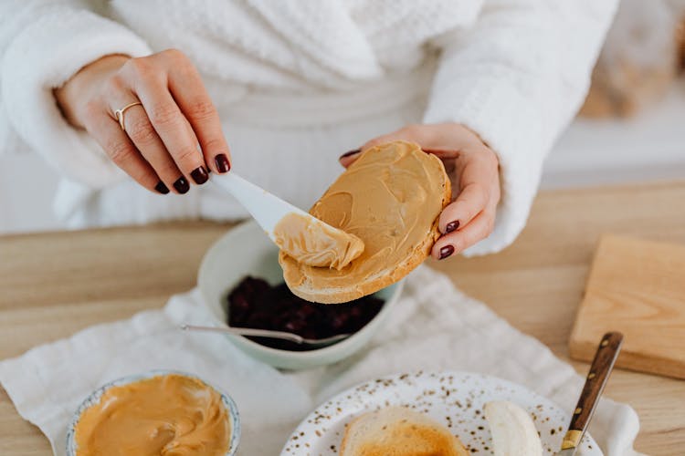 Person Spreading Peanut Butter On Toast 