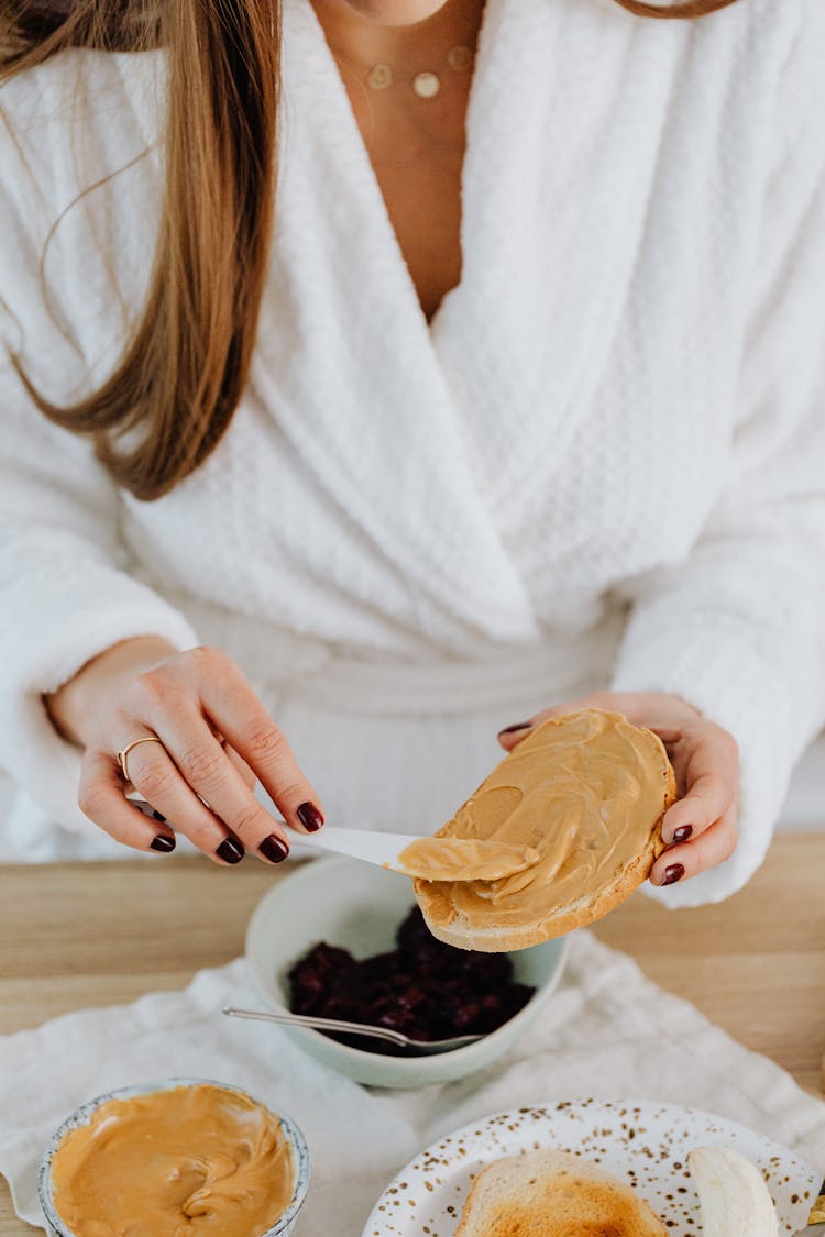 Woman Spreading Peanut Butter On Toast 