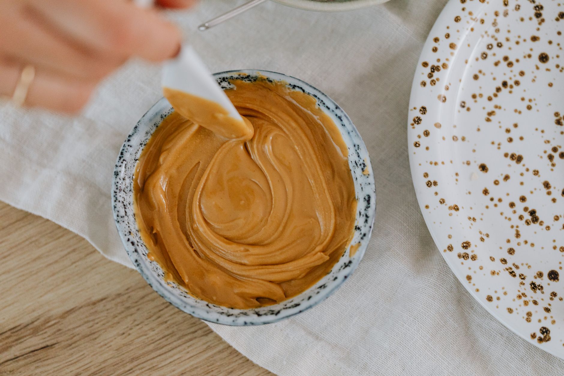 Quick Energy Balls: Your New Go-To Snack for Mornings A creamy swirl of peanut butter captured in a ceramic bowl from above.