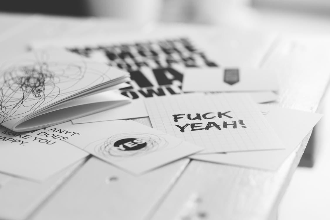 Black and white paper note cards. One card has scribbles on it and another says "Fuck Yeah!"