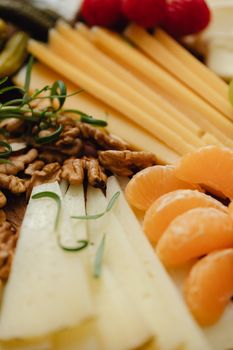 Close-up of a delicious assortment of cheeses, fruits, and walnuts, ideal for gourmet presentation.