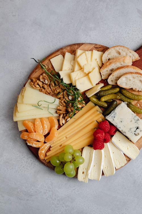 Free Elegant cheese and charcuterie board with fruits, nuts, and bread on a wooden platter. Stock Photo