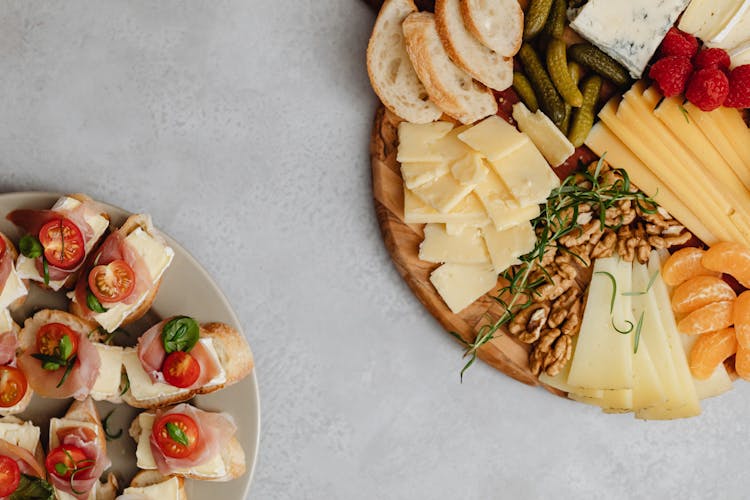 An Assorted Foods On A Charcuterie Board And A Ceramic Plate