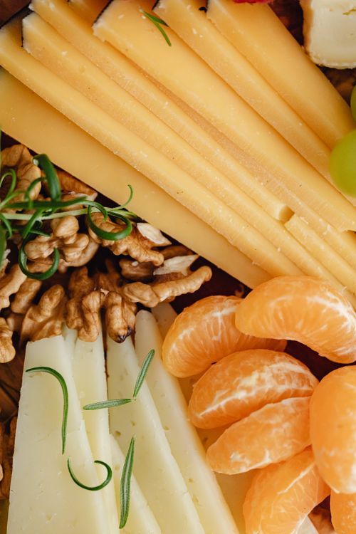 Free Close-up of sliced cheese, mandarin, and walnuts for a nutritious snack. Stock Photo