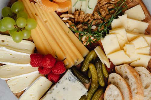 Free A delicious assortment of cheeses, fruits, nuts, and bread arranged on a charcuterie board. Stock Photo