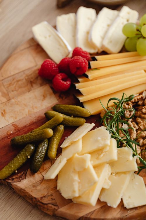 Free A delectable cheese board featuring cheeses, fruits, pickles, and nuts. Stock Photo