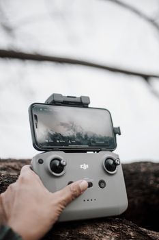 Detailed view of a hand operating a drone controller with a mounted smartphone outdoors.
