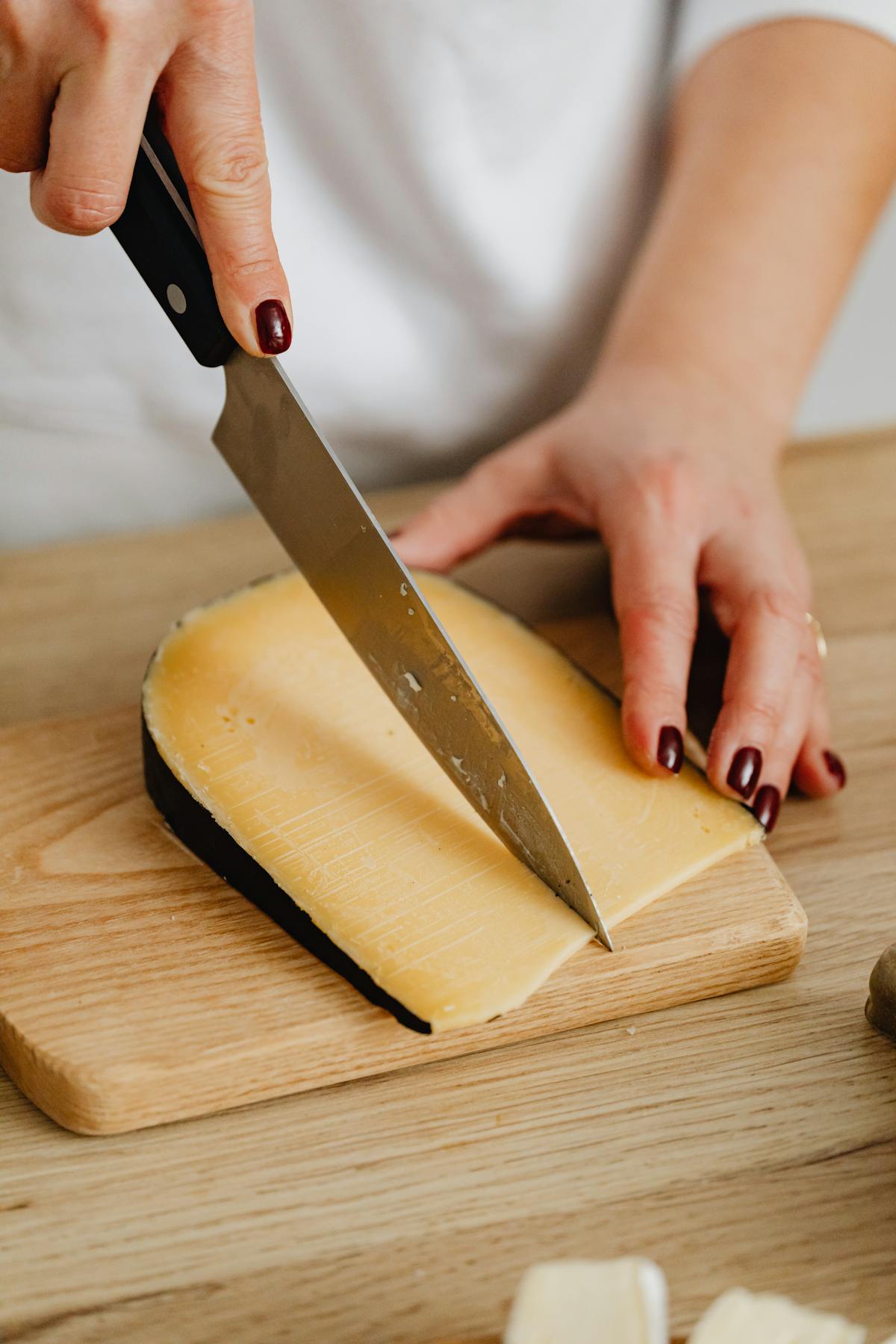 Persona che affetta delicatamente formaggio a spicchi su tagliere di legno